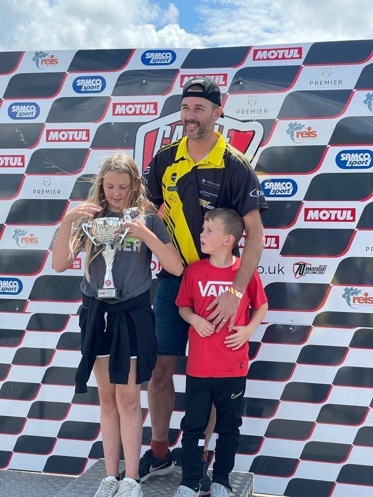 Shaun Deacon from ES Racing Solutions with his two children, holding a trophy